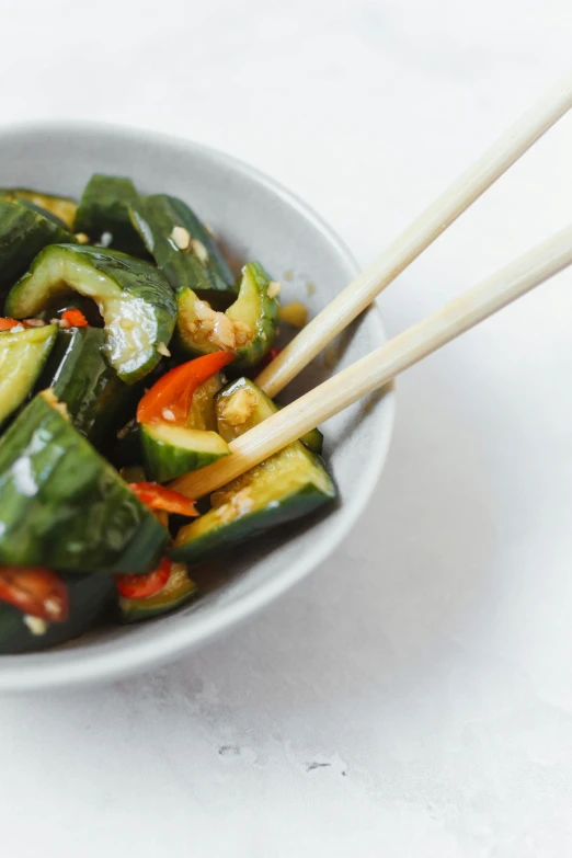 a close up of a bowl of food with chopsticks, pickle, square, f / 2 0, adi meyers