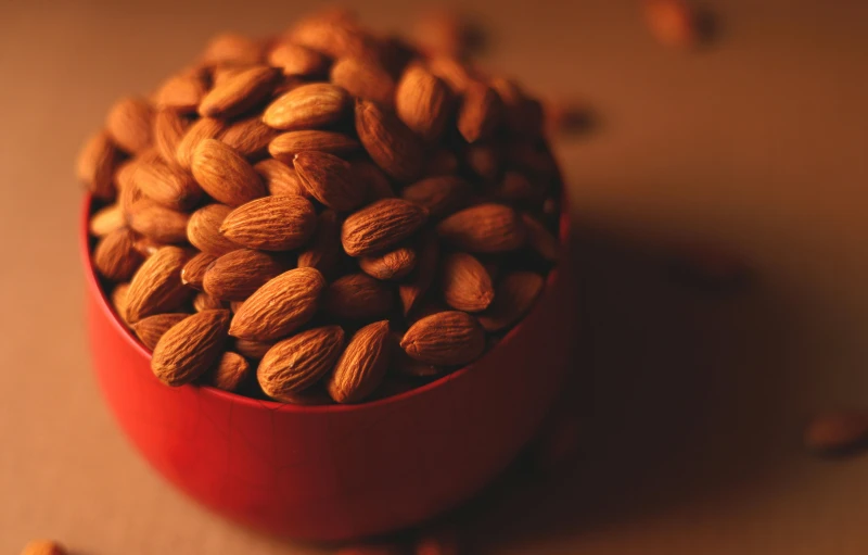 a red bowl filled with almonds on top of a table, pexels, 🦩🪐🐞👩🏻🦳, close-up product photo, high-resolution photo, medium close-up shot