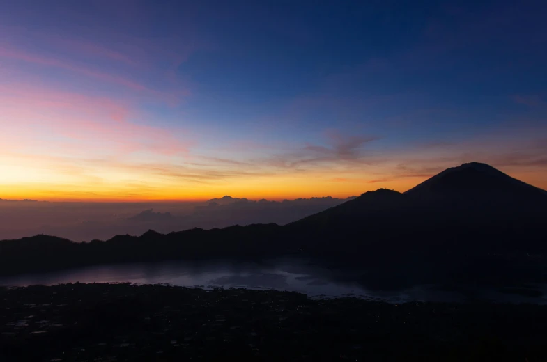 a hill covered with fog under a purple and yellow sky