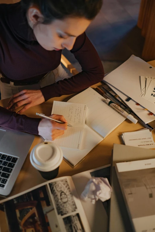 a person on a laptop and several papers on the table