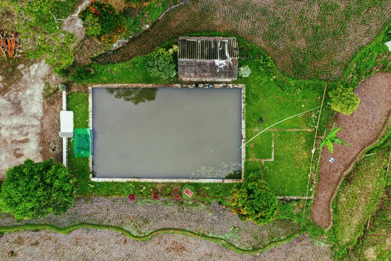 an aerial view of a pool in the middle of a field, an album cover, unsplash, background: assam tea garden, watertank, backyard, slight overcast