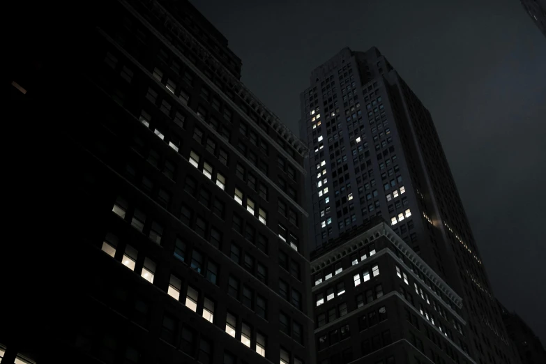 a group of tall buildings lit up at night, by Andrew Domachowski, photorealism, dark eerie photograph, ignant, ansel ]