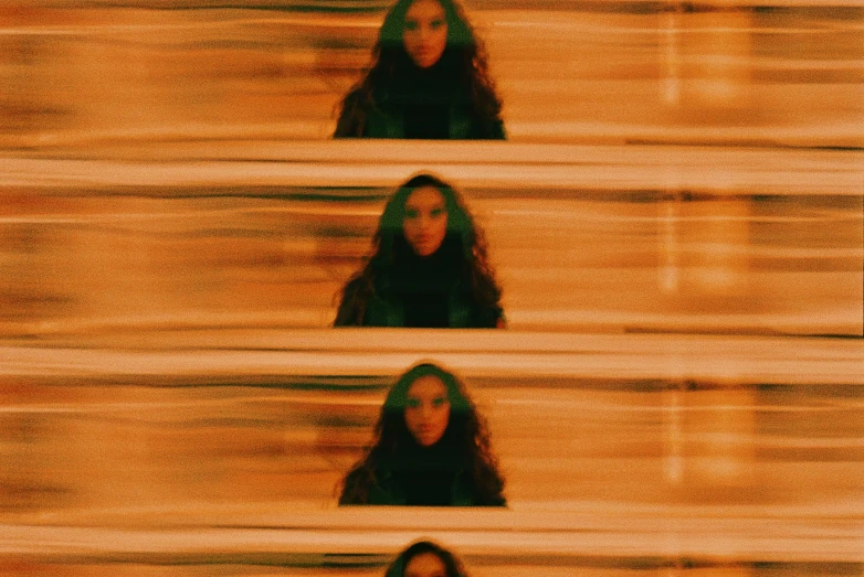 a blurry photo of a woman with long hair, video art, zoë kravitz, repeating 3 5 mm photography, orange tones, symmetrical image