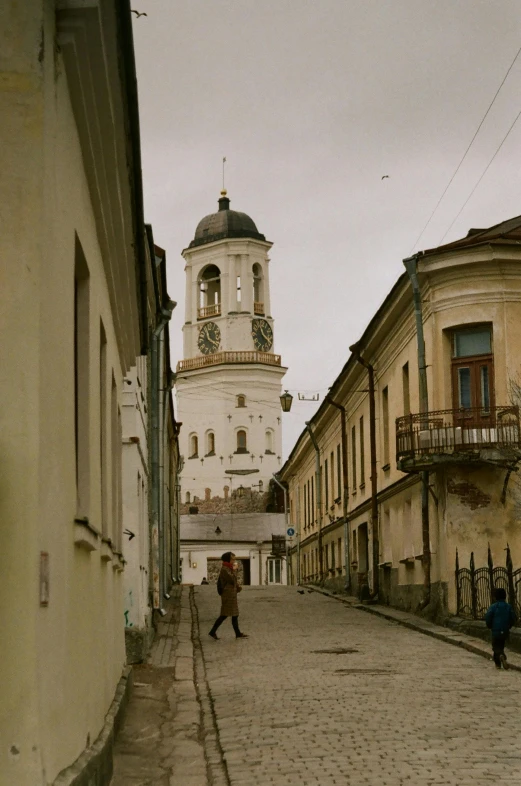 a couple of people walking down a cobblestone street, inspired by Mikhail Yuryevich Lermontov, neoclassical tower with dome, southern slav features, in town, cinematic lut