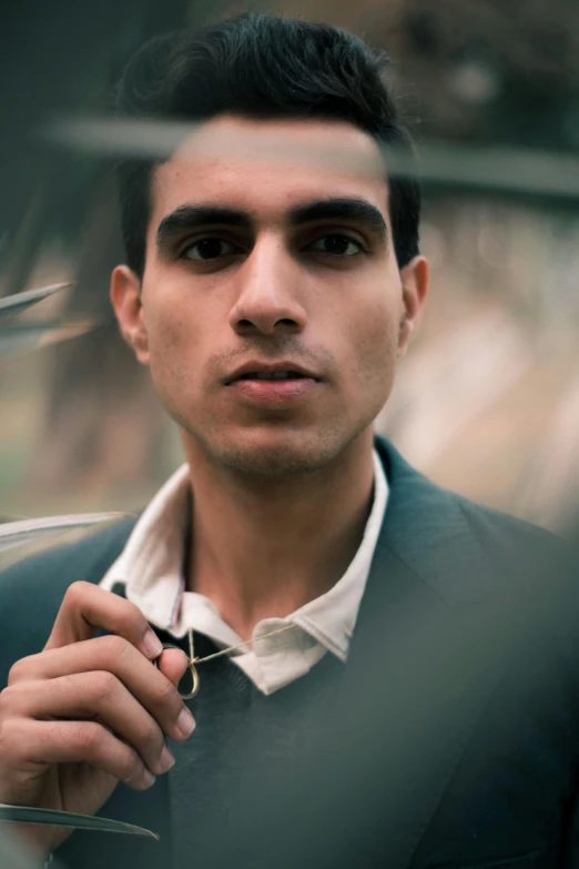 a close up of a person wearing a suit and tie, an album cover, inspired by Ahmed Yacoubi, unsplash, clean - shaven, casually dressed, transgender, arab