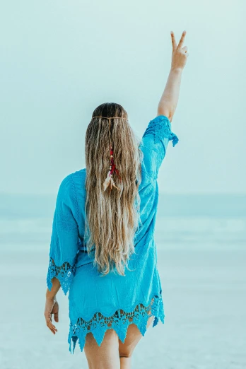 woman walking on the beach while holding her hands up in the air