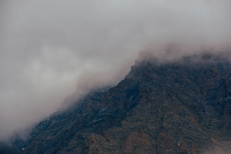 some mist rolling over the top of a mountain side