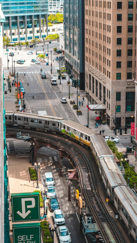 a train traveling through a city next to tall buildings, by Robbie Trevino, unsplash contest winner, wisconsin, square, panoramic, high angle view
