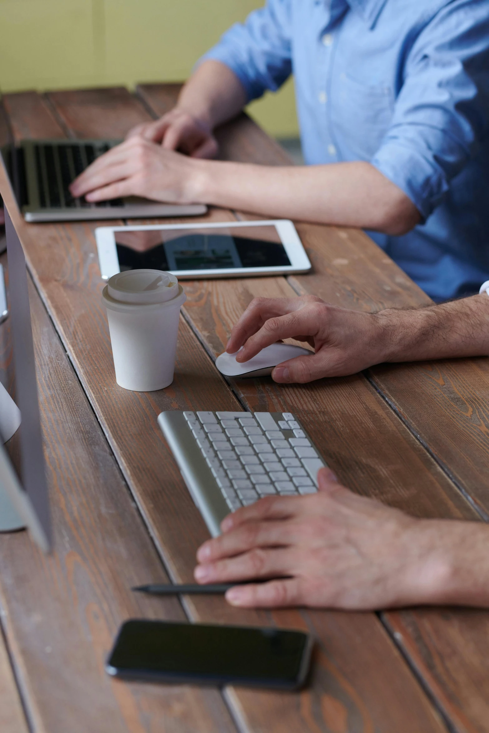 a group of people sitting around a wooden table, a digital rendering, pexels, keyboards, square, commercial, rustic