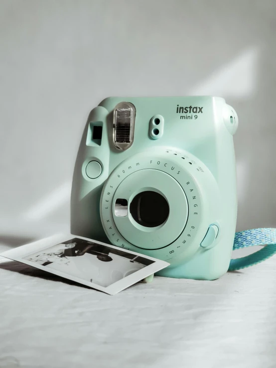 a polaroid camera sitting on top of a bed, ((greenish blue tones)), vines. tiffany blue, 5k, portrait n - 9