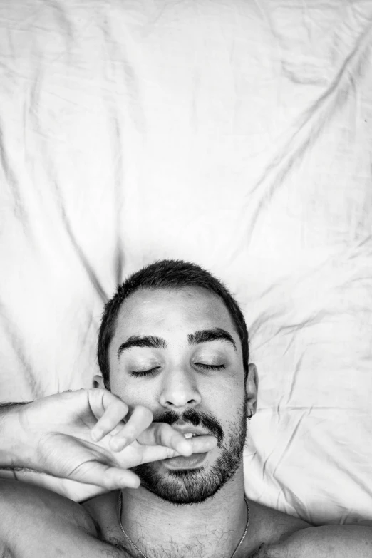 man with hand on forehead making gesture while under unmade bed