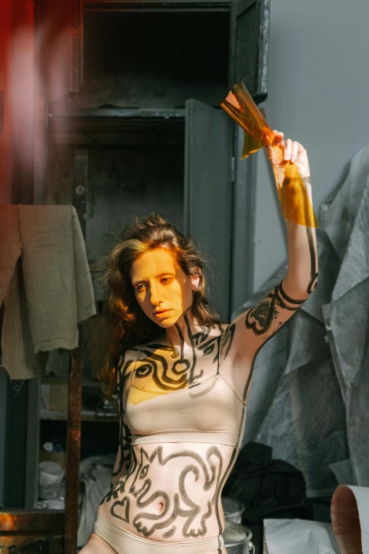 a woman in a body paint posing for a picture, inspired by Elizabeth Polunin, graffiti, holding a sacrificial dagger, in a workshop, ((messy)), gold clothes