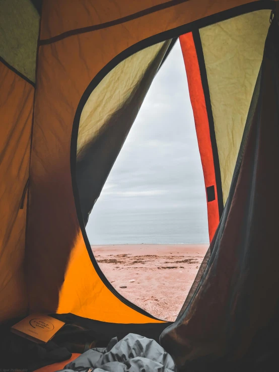 a view of the beach from inside a tent, by Jessie Algie, trending on unsplash, visual art, gray and orange colours, red sand, open windows, looking into camera