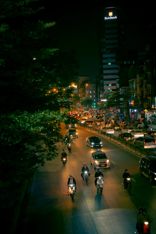 a city street filled with lots of traffic at night, riding a motorbike down a street, sparsely populated, touring, multiple stories