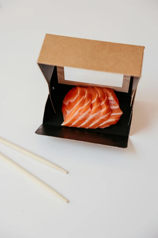 salmon in a small black cardboard box with chopsticks