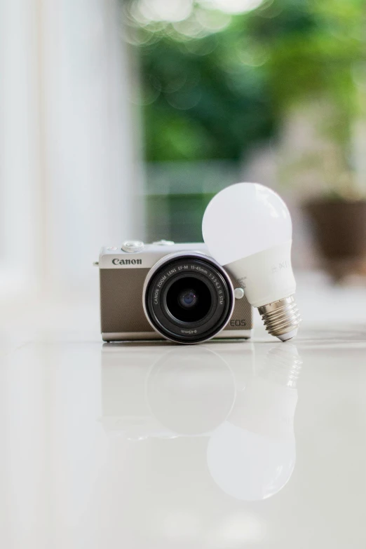 a camera sitting on top of a table next to a light bulb, canon eos m50, lumen, environmental shot, intelligent