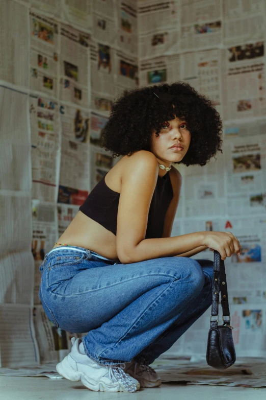 a woman squatting in front of a pile of newspapers, an album cover, by Lily Delissa Joseph, trending on pexels, renaissance, short black curly hair, daisy dukes, looking straight, asher duran