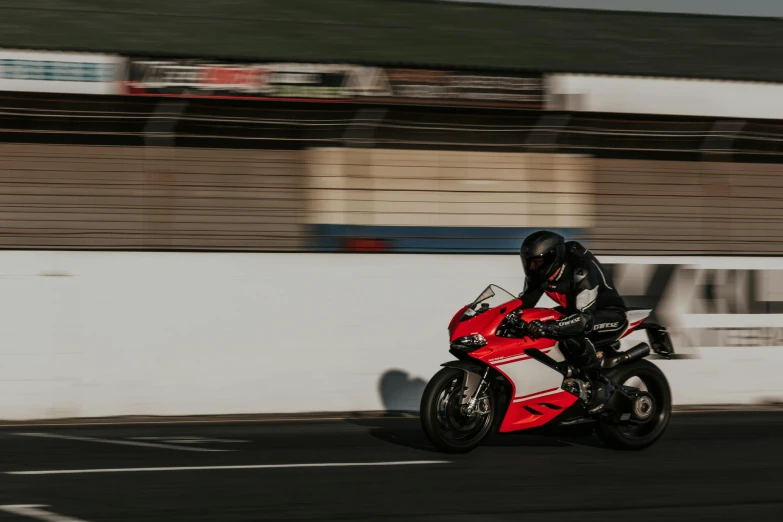 a man riding a red motorcycle down the street