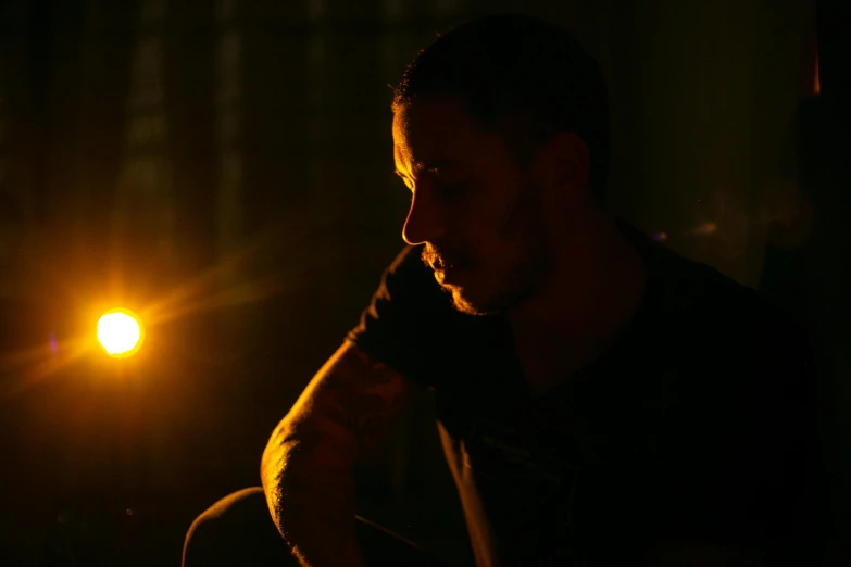 a man playing a guitar in the dark, a portrait, pexels contest winner, realism, tom hardy, pondering, lens flare photo real, candlelit