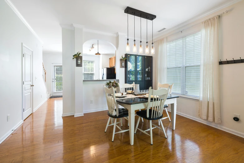 an open house has white curtains, hardwood floors, and modern lighting