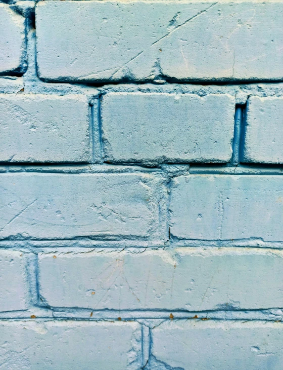 an image of a blue brick wall with a yellow bird perched on the ledge