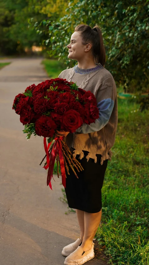 the woman is holding a huge bouquet of roses