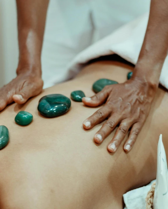 a woman getting a back massage with green stones, by Olivia Peguero, non-binary, malaysian, thumbnail, multiple stories