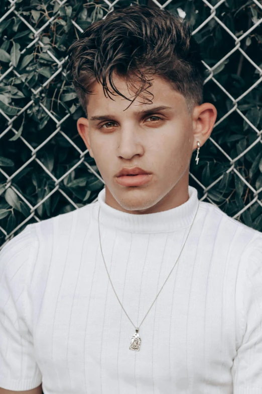 a young man standing in front of a chain link fence