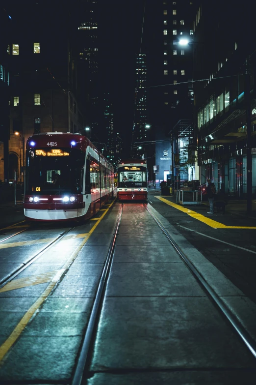 two red and white trains and buildings at night