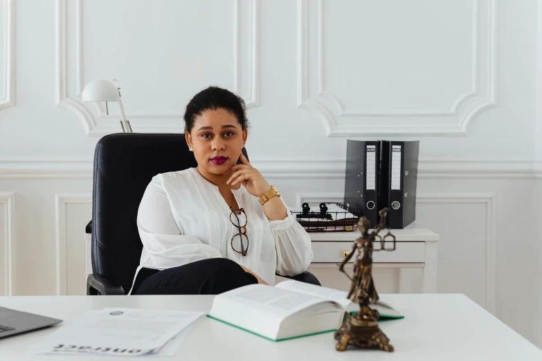 a woman sitting at a desk in front of a laptop computer, by Julia Pishtar, pexels contest winner, lawyer, in white room, african ameera al taweel, in paris