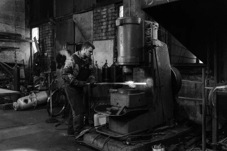 a black and white photo of a man working in a factory, by Stefan Gierowski, pexels contest winner, arbeitsrat für kunst, made of metal, 15081959 21121991 01012000 4k, during the night, punching