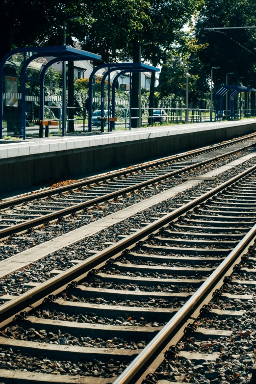 a train traveling down train tracks next to a train station, square, high-quality photo, medium-shot, waiting