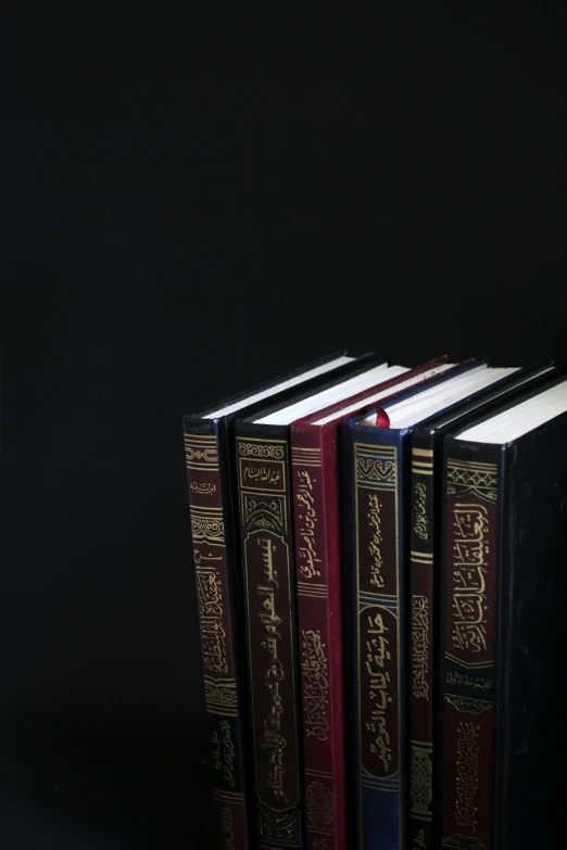 a stack of books sitting on top of a table, hurufiyya, standing with a black background, - 9