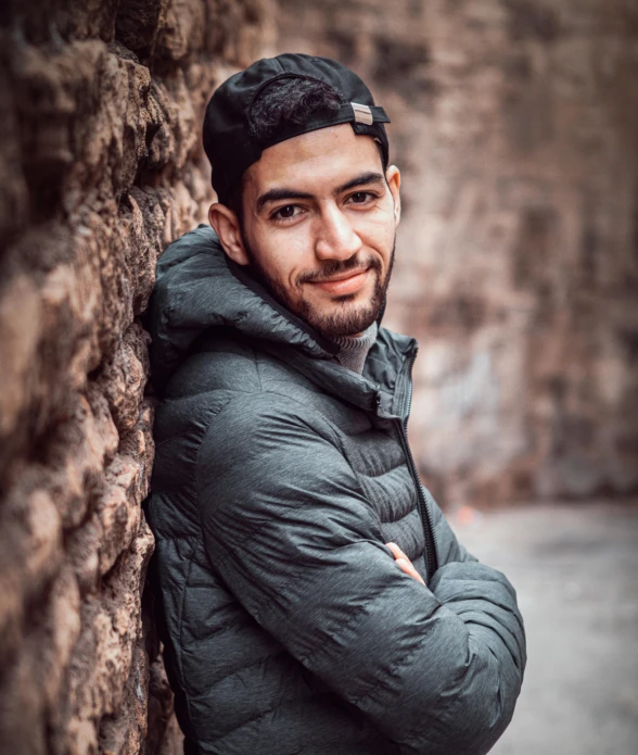 a man leaning up against a stone wall