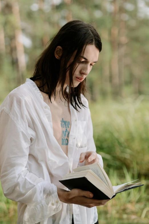 a woman in a white shirt is reading a book, by Grytė Pintukaitė, trending on unsplash, forest ritual, non binary model, avatar image, shirt