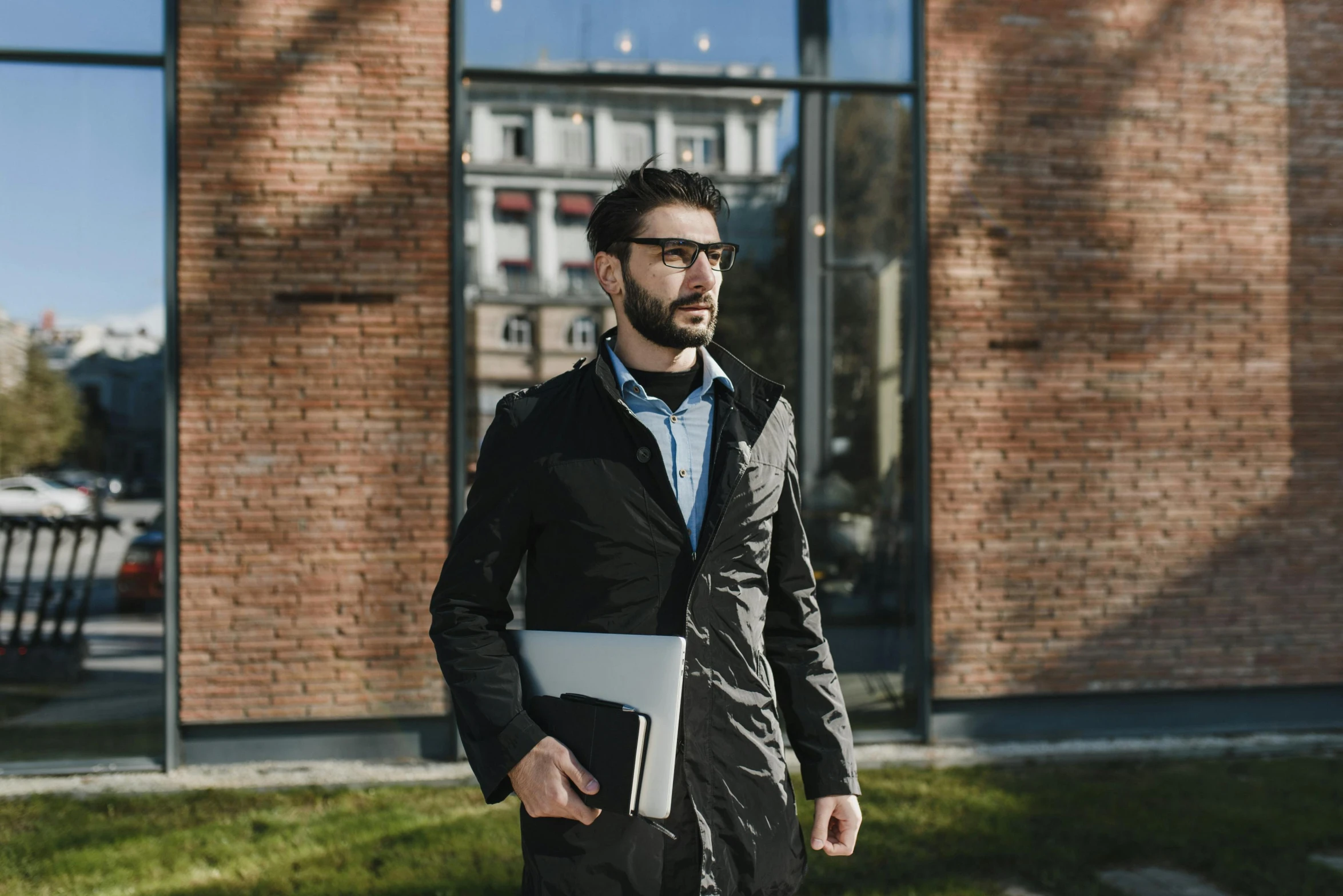 a man standing on grass with a laptop in his hand