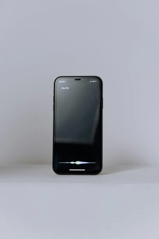 a black cell phone sitting on top of a table, a hologram, by Adam Rex, unsplash, on a gray background, iphone 12, full front view, low quality photo