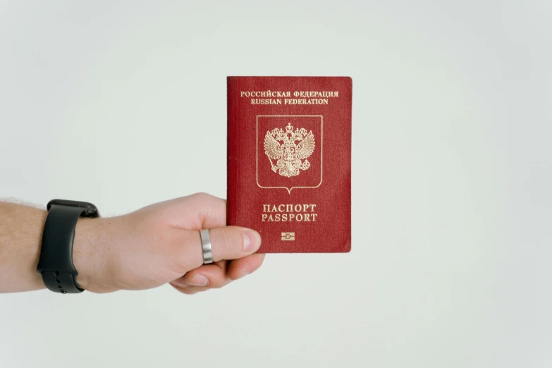 a man is holding up a red passport