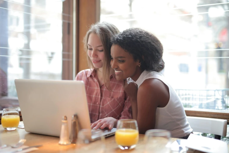 two women sitting at a table looking at a laptop, trending on pexels, profile pic, brown, high quality image, thumbnail