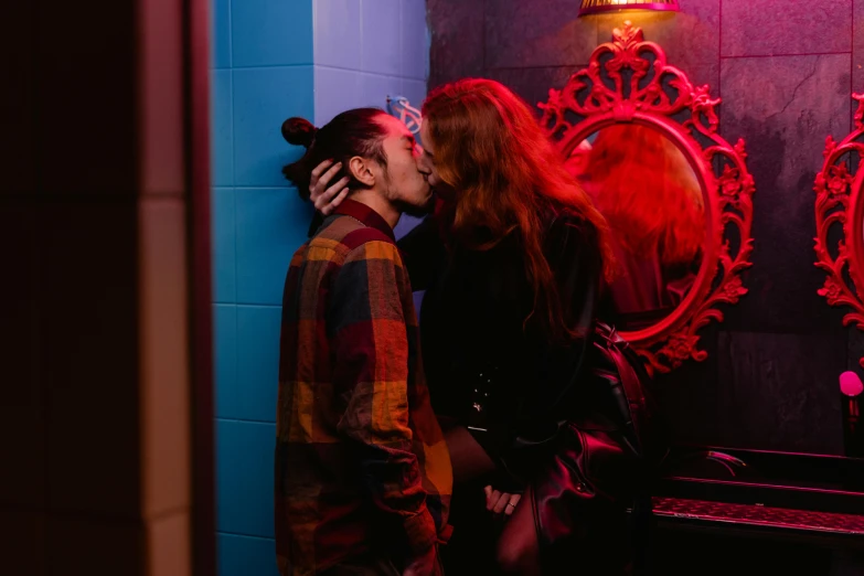 a man and a woman kissing in front of a mirror, red and blue black light, brunette boy and redhead boy, lachlan bailey, in a bathroom