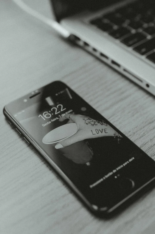 a cell phone sitting on top of a table next to a laptop, a black and white photo, trending on pexels, love, iphone wallpaper, your personal data avatar, black design