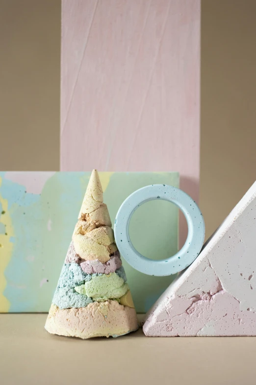 a couple of ice cream cones sitting on top of a table, an abstract sculpture, inspired by Yanjun Cheng, pastel texture, halo / nimbus, made of concrete, detailed product image