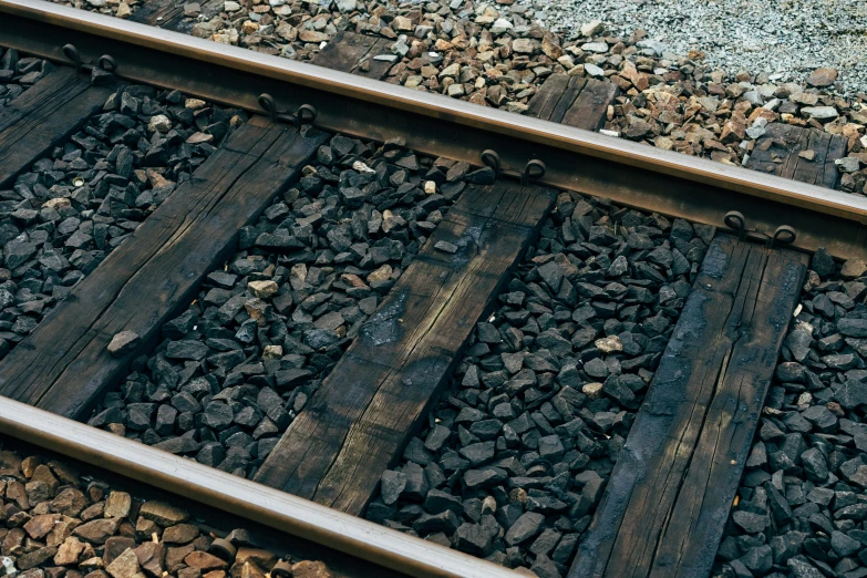 a red fire hydrant sitting on top of a train track, an album cover, by Carey Morris, unsplash, photorealism, with lots of dark grey rocks, black vertical slatted timber, made of tar, detail render