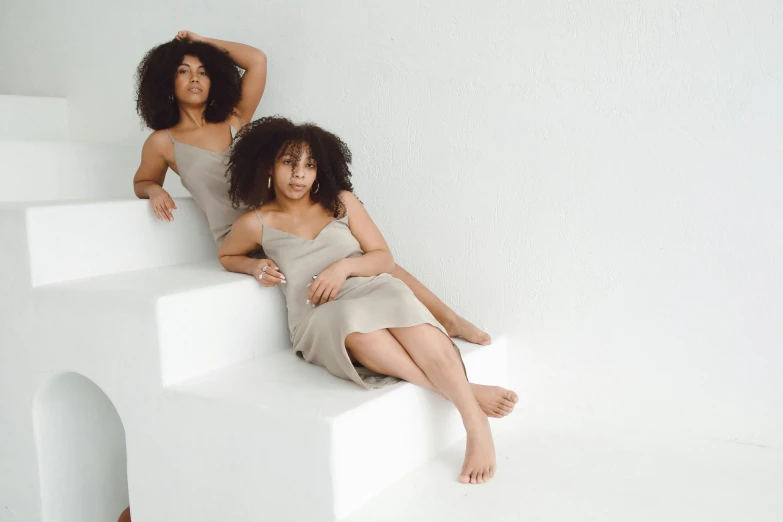 two women sit on white steps together