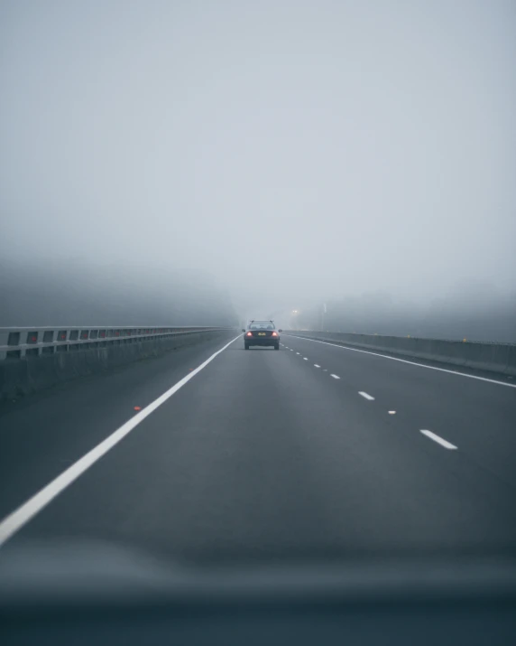 a dark, foggy road with cars going down it