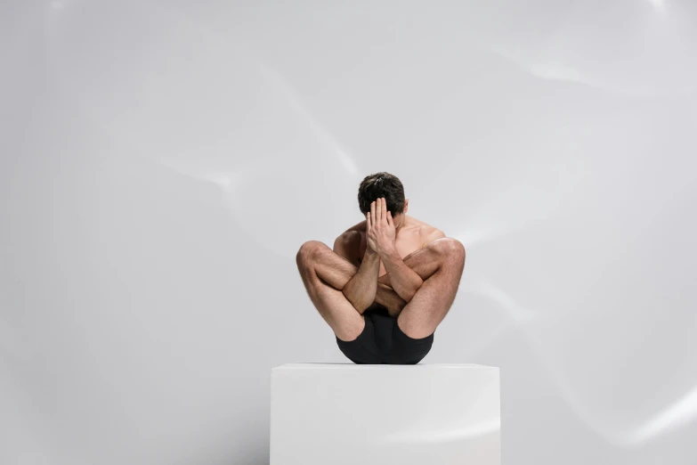 the man is sitting on the cube and holding his head