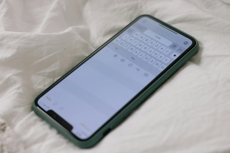 an iphone x sits in the middle of a bed with a white sheet