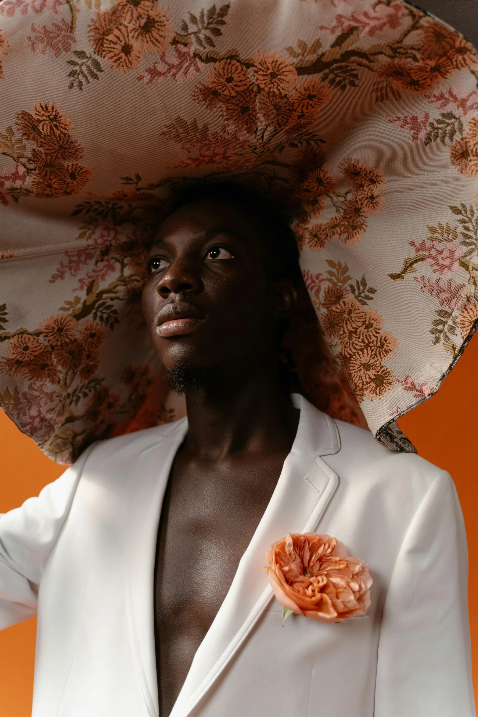 a man with a large hat and an orange flower on it