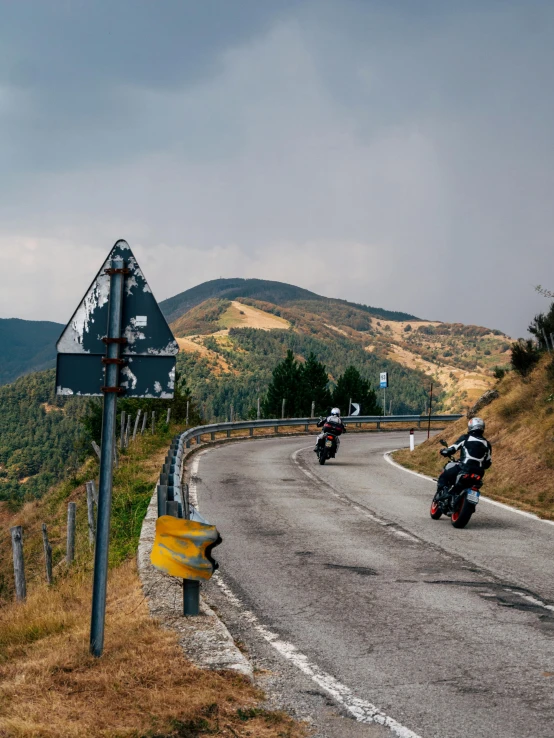 three motorcycles driving down the road, one is going to a turn