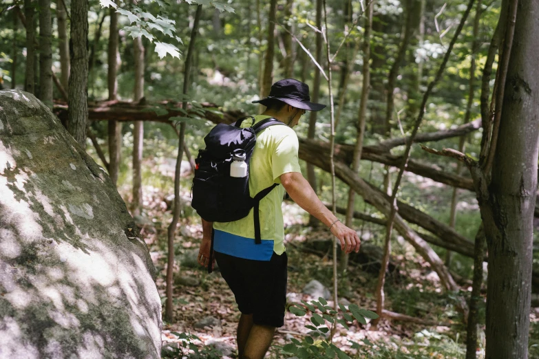 a man with a back pack is climbing up a tree in the woods